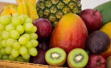 red apple fruit beside green apple and yellow fruit on brown woven basket